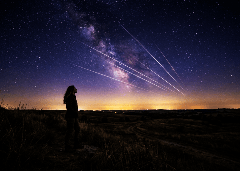 Woman on open prairie watching the Perseid meteor shower streak across a moonless night sky in August 2026